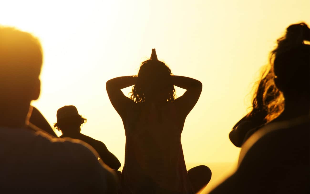 a sunset image of people doing yoga in the yellow light