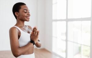 a woman with her hands in prayer wearing white yoga clothes