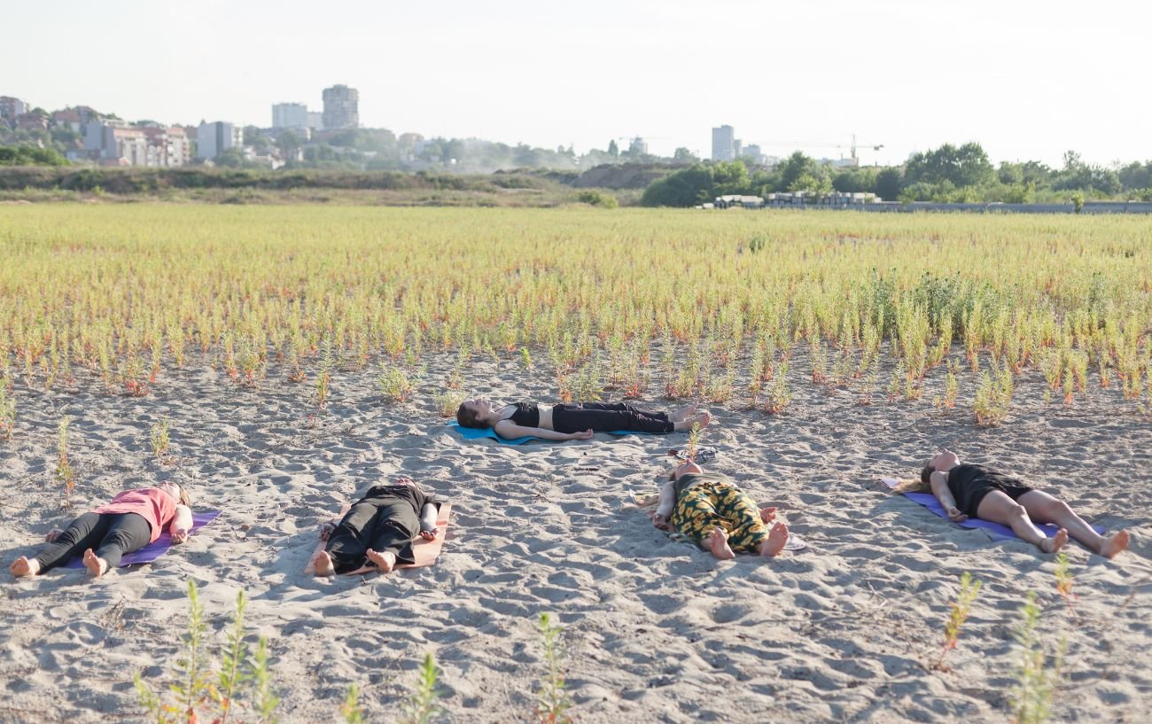 group of yogis in savasana on sand