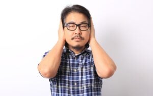 a man wearing glasses holding his hands over his ears