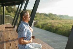 Woman sitting in quiet meditation with eyes closed, practicing yoga breathing to calm tinnitus